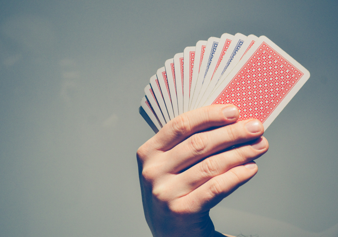 A hand holding a fan of red- and blue-backed playing cards.